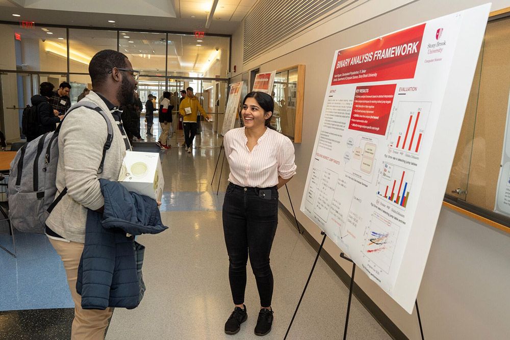 Graduate students presenting computer science research projects on posters at the New Computer Science Building