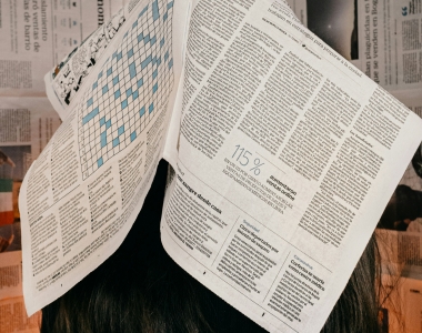 a person lays an open newspaper across their face